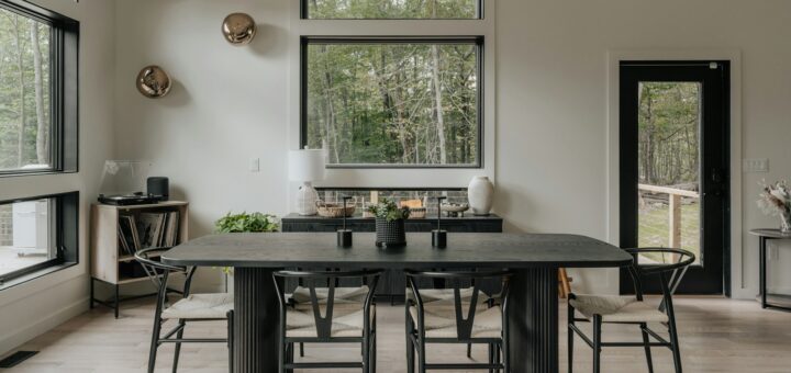 Tavolo da pranzo nero con sedie nere in una sala luminosa con parquet chiaro