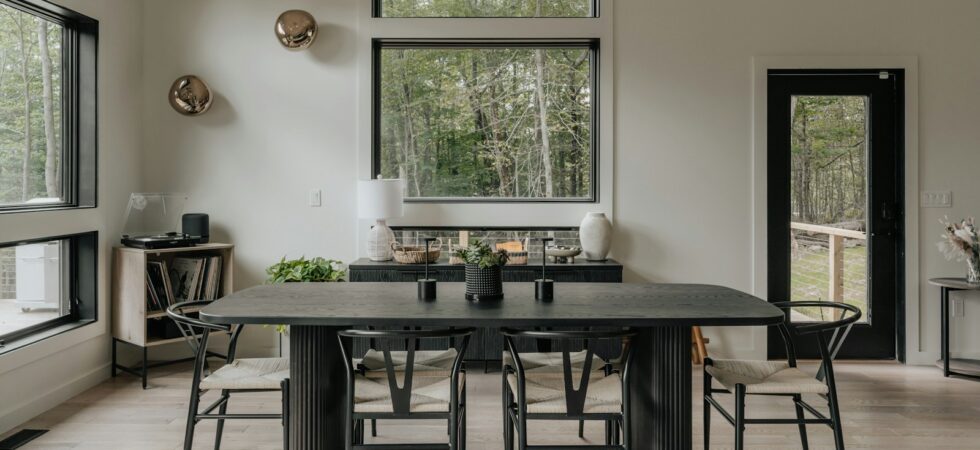 Tavolo da pranzo nero con sedie nere in una sala luminosa con parquet chiaro