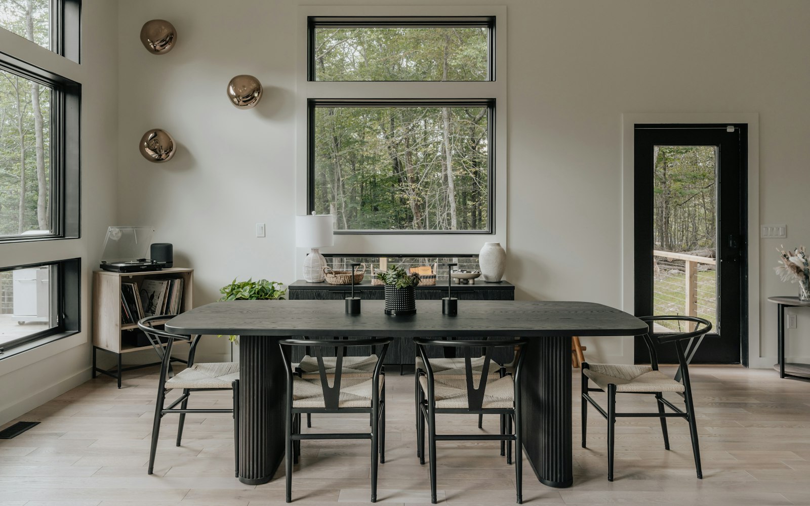 Tavolo da pranzo nero con sedie nere in una sala luminosa con parquet chiaro