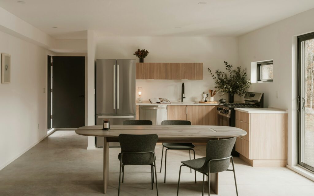 Tavolo ovale in legno con sedie verdi in un open space con cucina