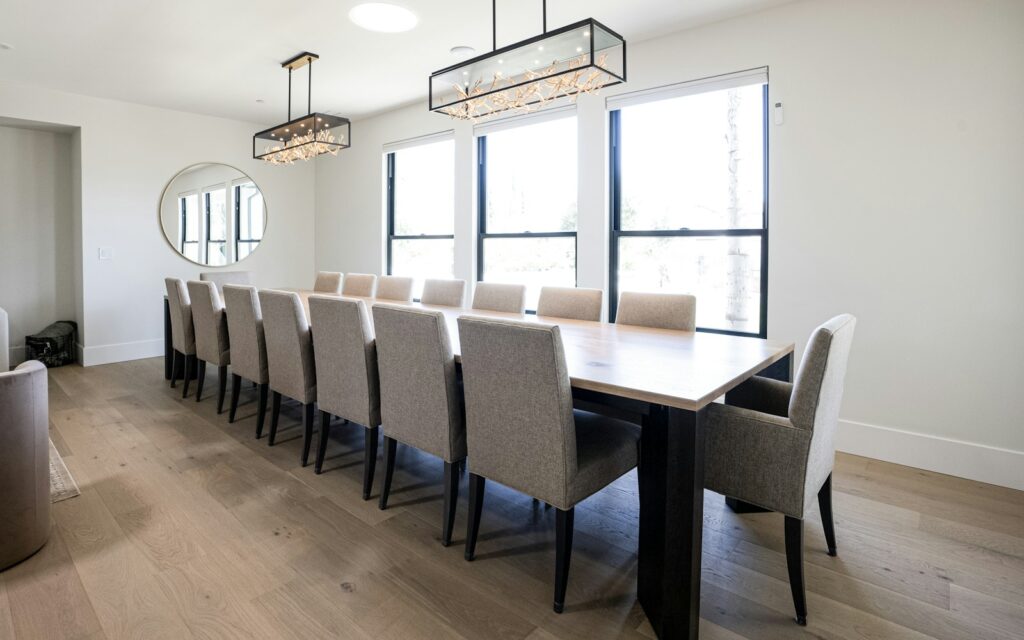 Lungo tavolo da pranzo in legno con due sospensioni geometriche allineate sopra